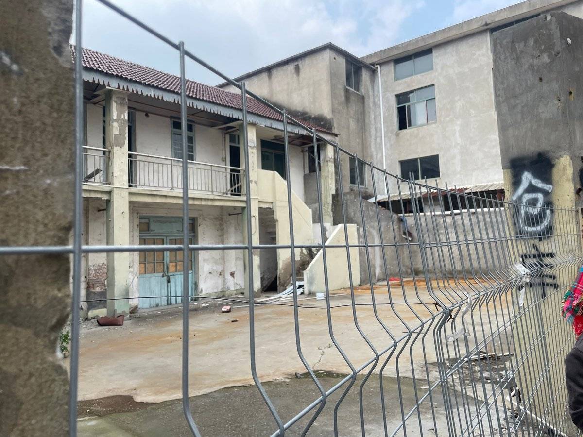 仮囲いのフェンス越しに見える解体中の二階建ての建物