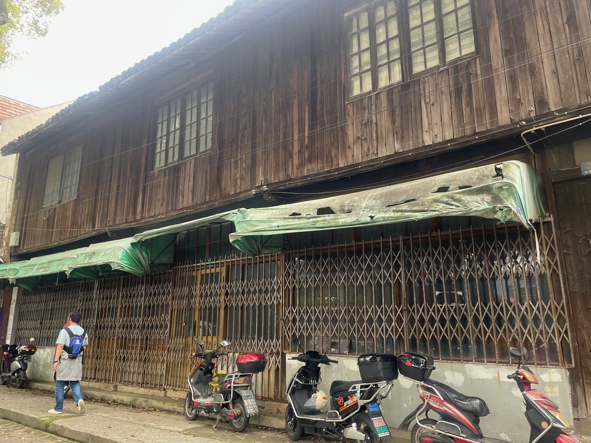 永定南路の木造二階建ての商店建築。蛇腹シャッターと緑のひさしが続く